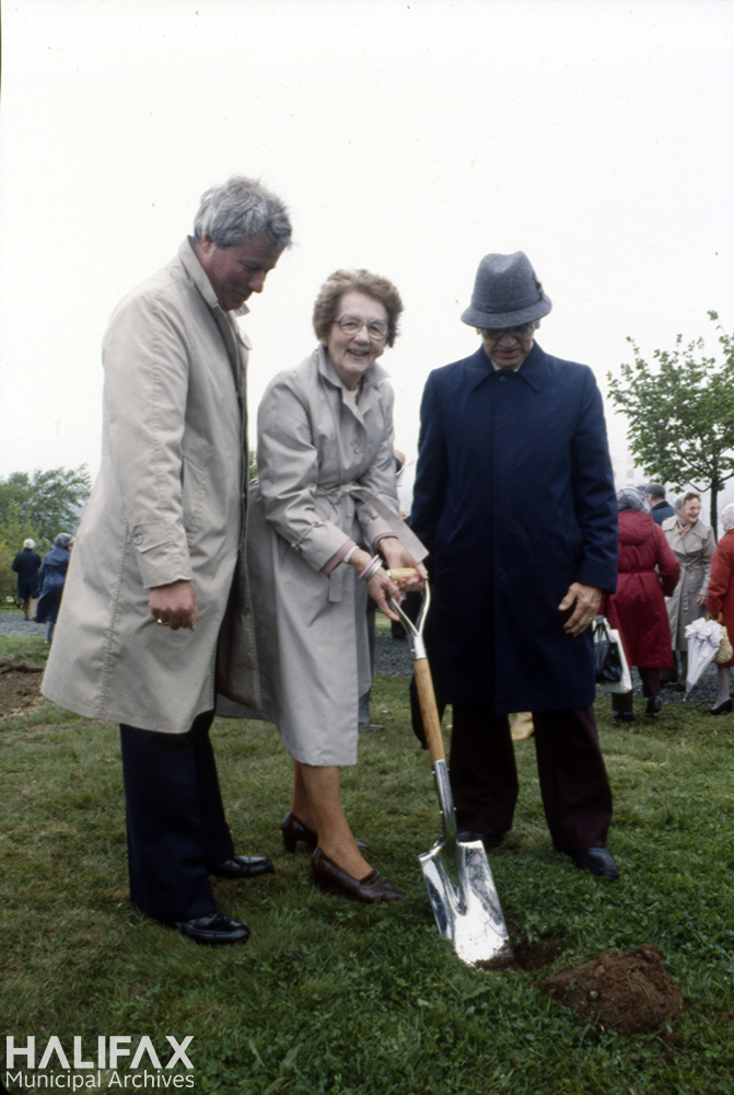 Colour photograph of a woman and two men posing with a shovel at a sod turning ceremony.