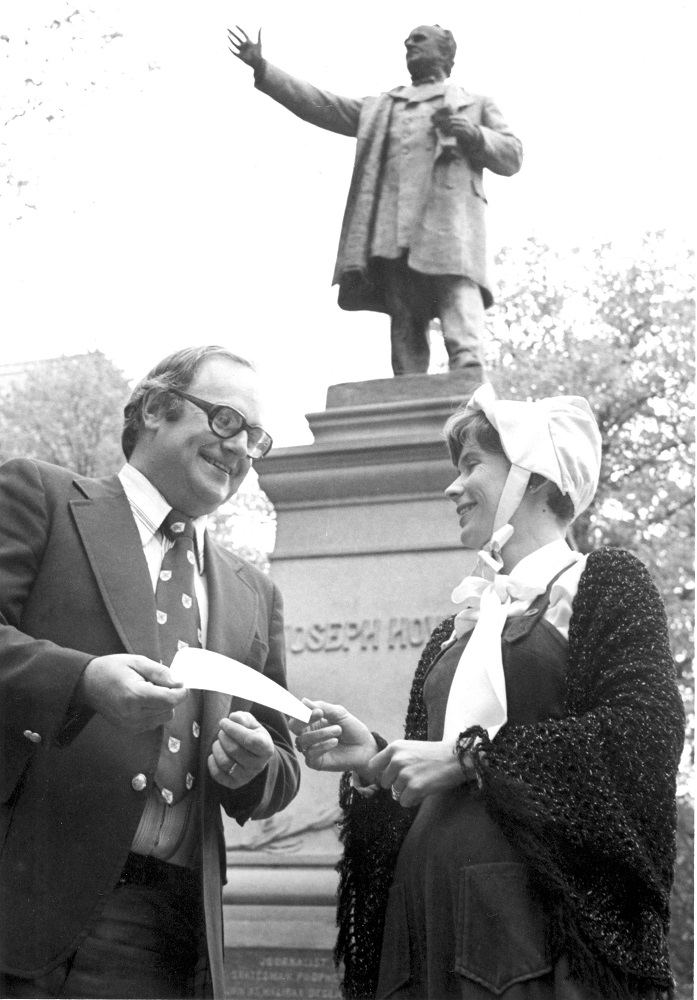 Black & white photo of Mayor Walter Fitzgerald presenting a cheque to Festival Vice-President, Carolyn Amirault in front of the Joseph Howe statue in the courtyard of Province House, 1978.