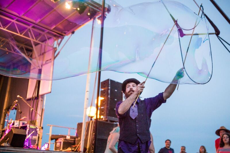 A man creates a giant bubble with a bubble wand at Bedford Days.