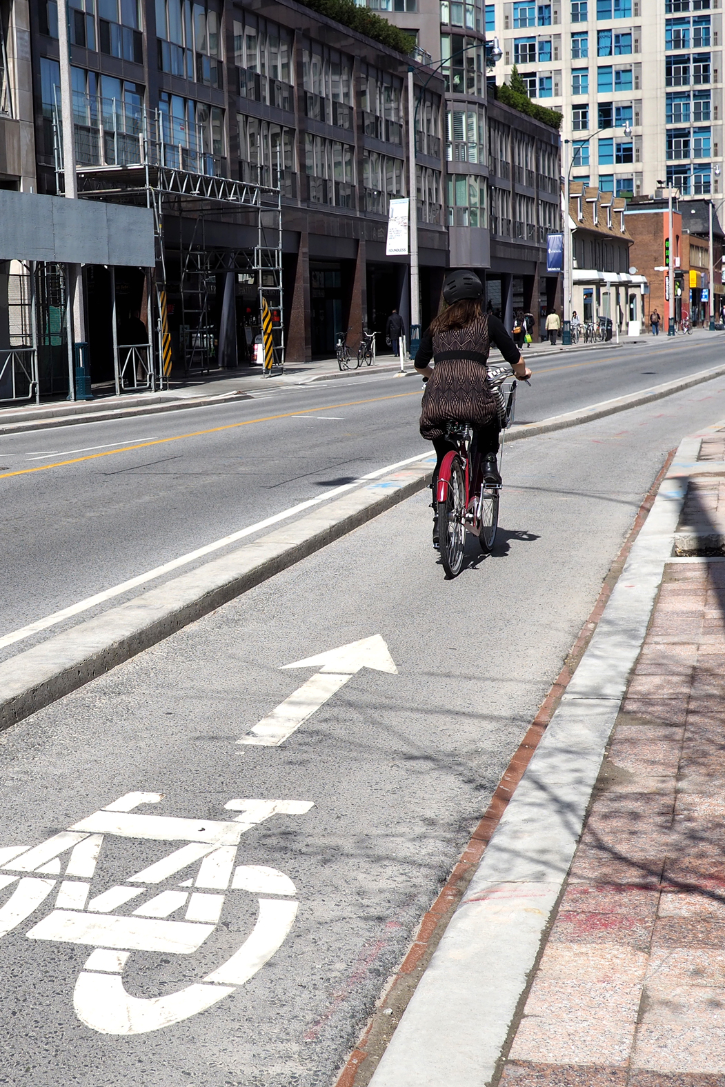 Woman cycles in Toronto on a protected bicycle lane.