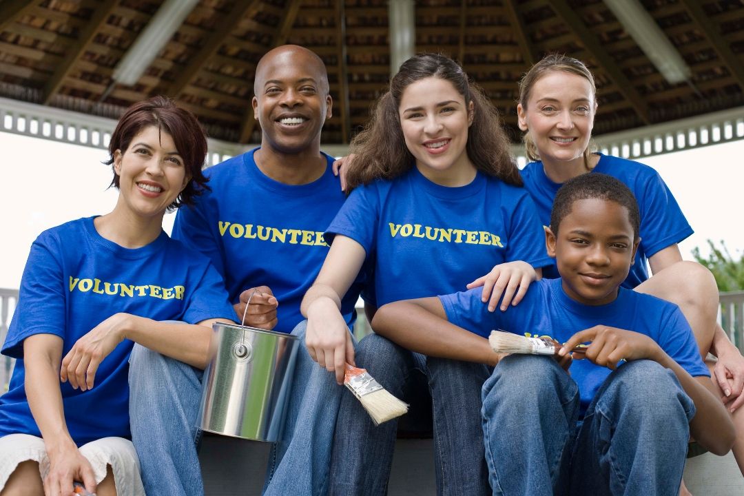 a group of volunteers sitting together with paint brushes