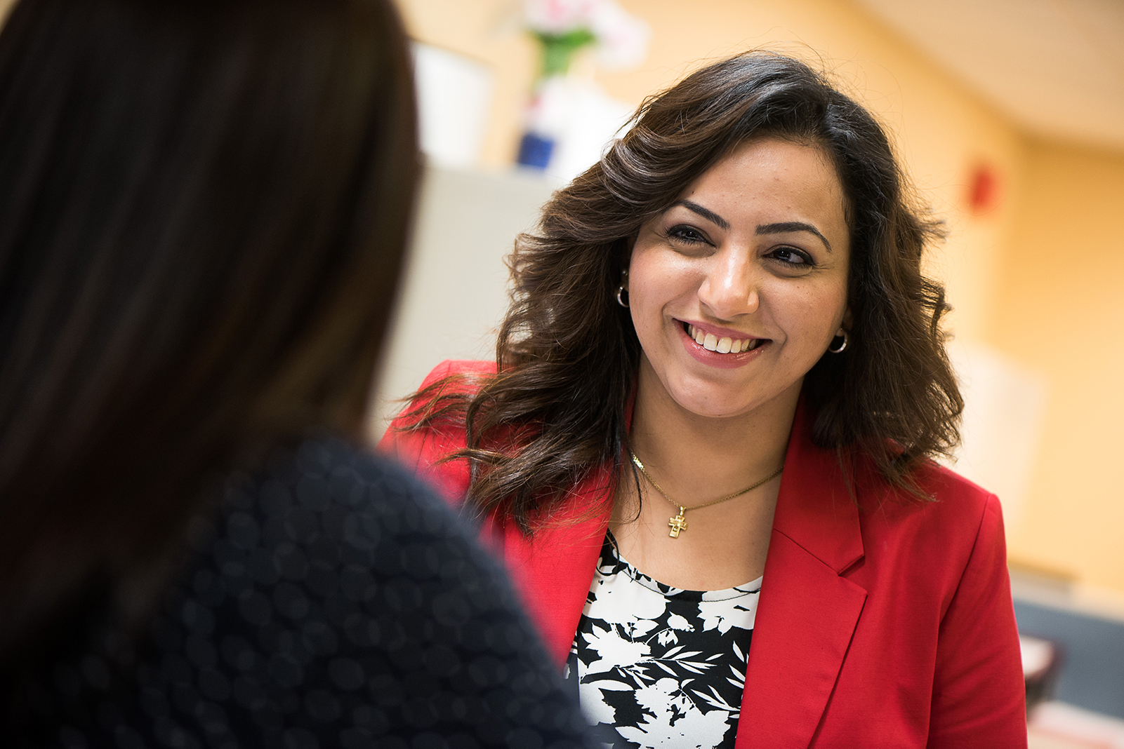 A photo of a woman smiling and talking to someone in the foreground