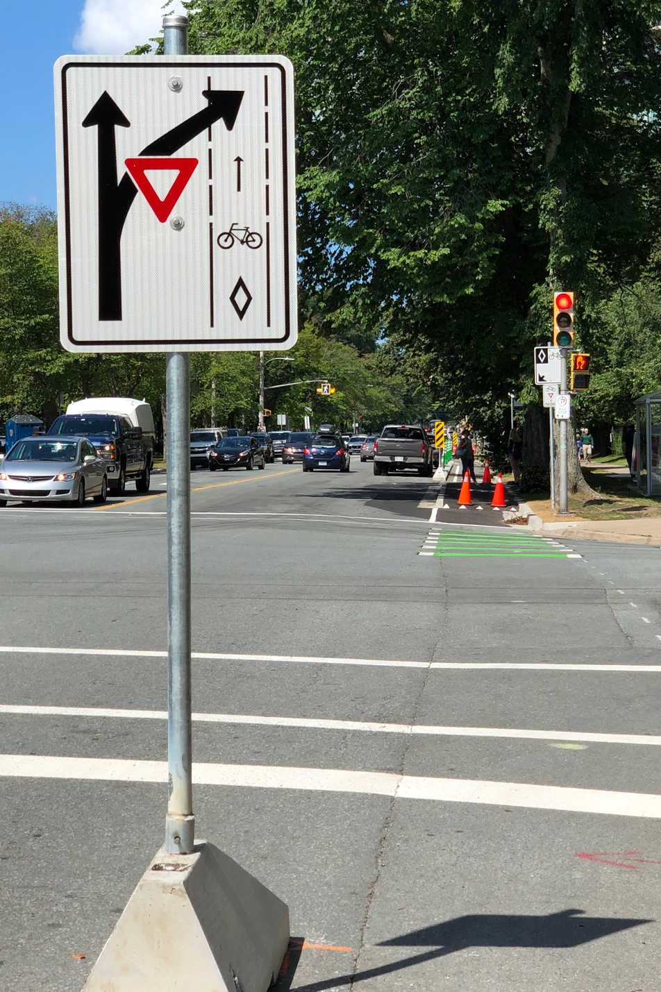 A photo of a roadsign indicating how cyclists should cross an intersection, with a yield sign for vehicle traffic.