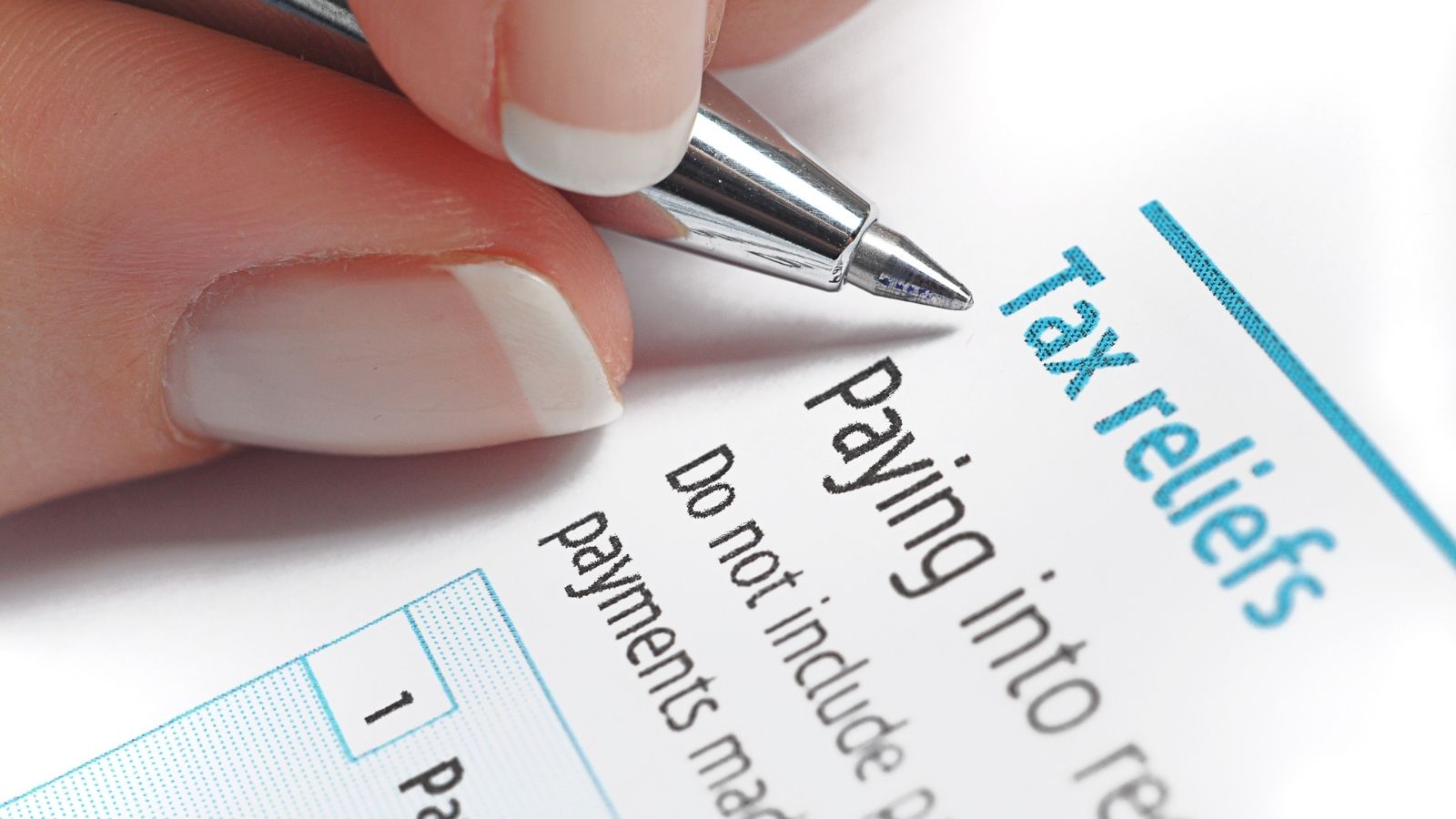 A hand holds a pen over a piece of paper with the heading "tax Relief"