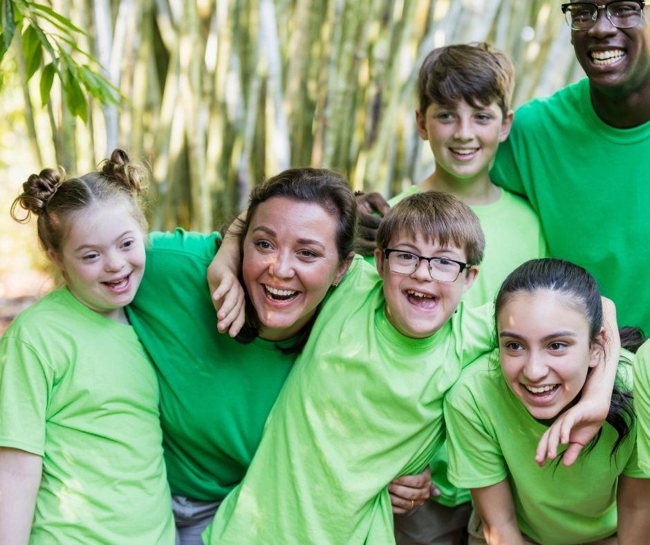 A group of inclusion support workers huddles together with children