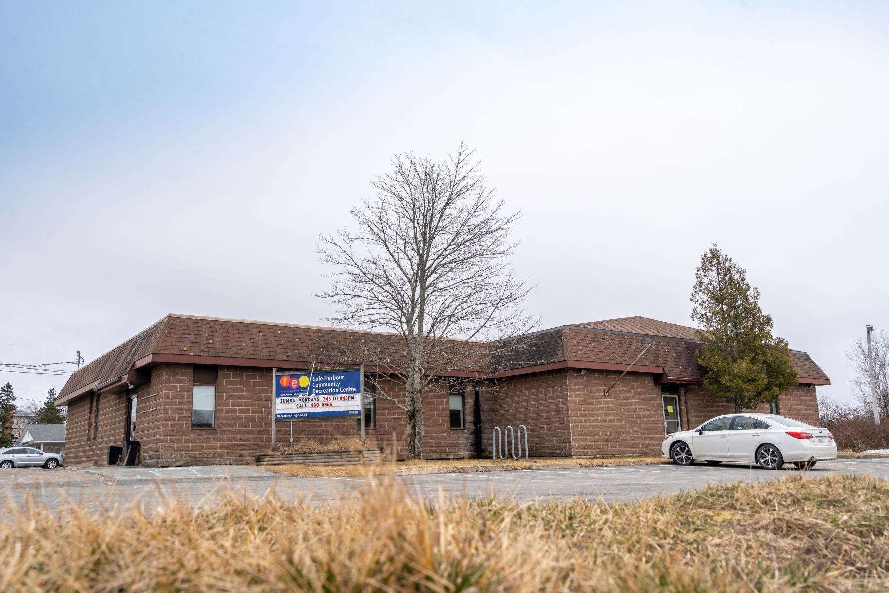 The exterior front entrance of the Cole Harbour Rec Centre with a white car parked in front