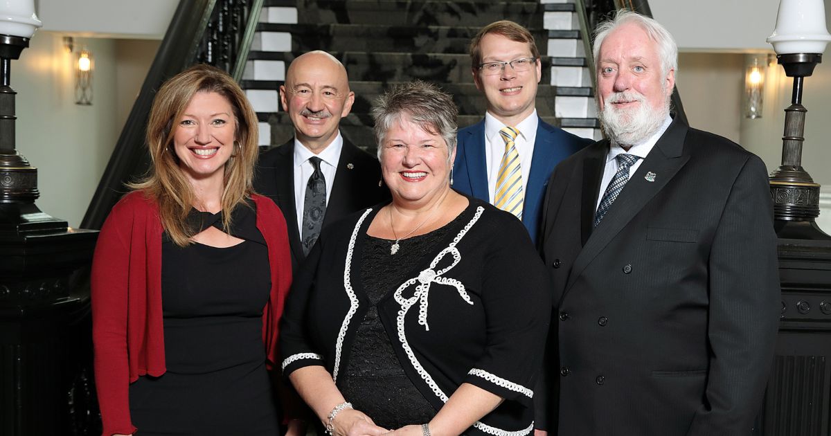 Members of Regional Council stand together in front of the stairs inside City Hall