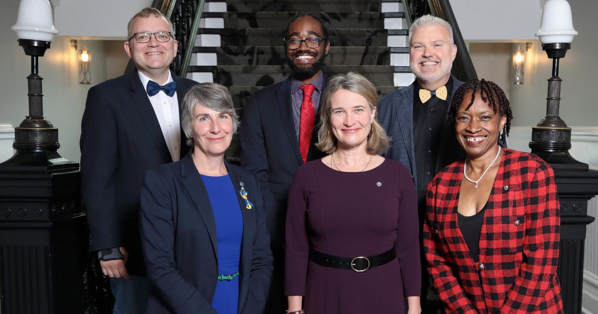 Members of Regional Council stand together in front of the stairs inside City Hall