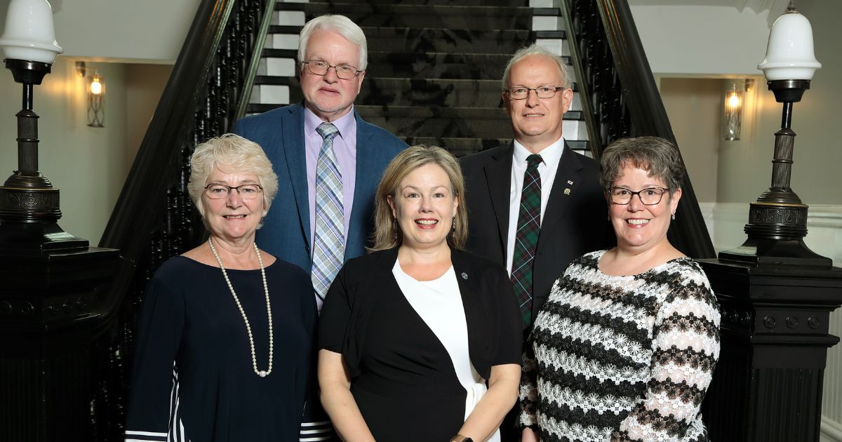 Members of Regional Council stand together in front of the stairs inside City Hall