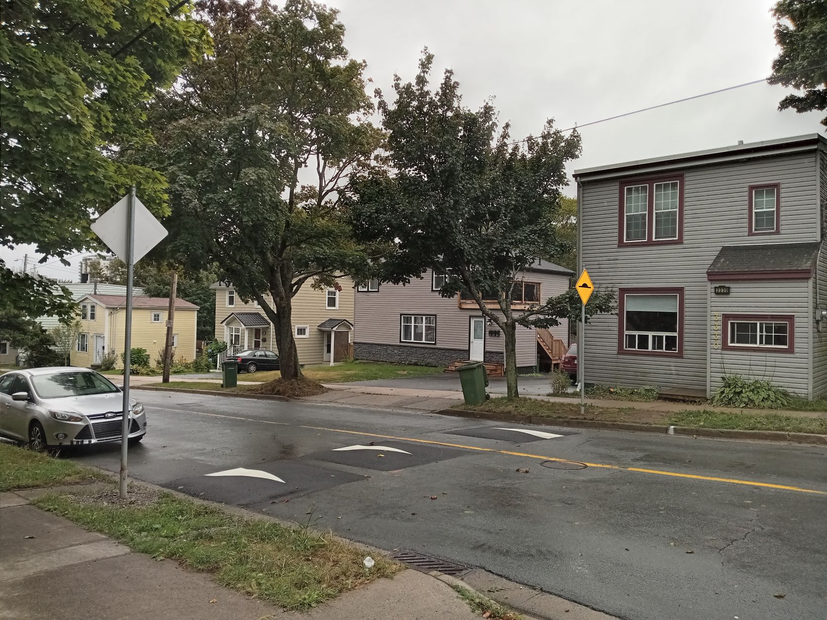 A photo of a street with a set of three speed cushions installed across the travel lanes.