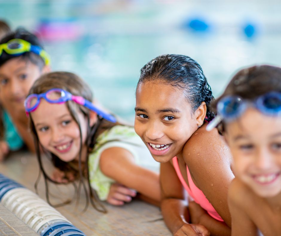 a group of young teens in a pool leaning over the side