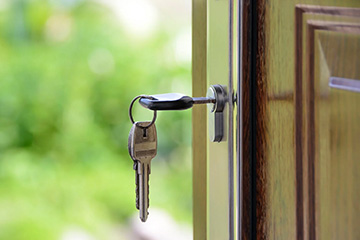 An image of a key hanging out of the keyhole of a wooden door with a green background