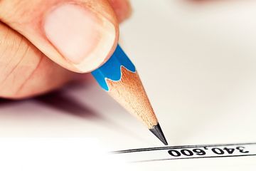 a close up of a hand holding a pencil makes a note beside a figure on a piece of paper