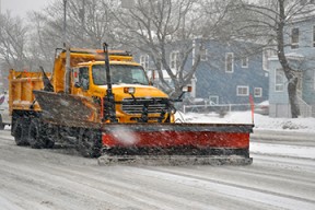 photo of snow plow clearing a residential street during a snow storm