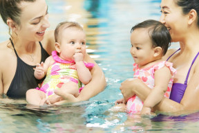 Two moms with babies in the swimming pool. 