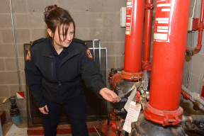 A female Fire Inspector inspects heating equipment ensuring that it is up to standard. 