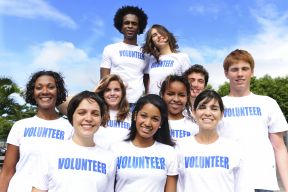 A group of people smile while wearing identical volunteer shirts