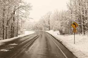 A stretch of road, cleared by a snowplow, is seen in winter.